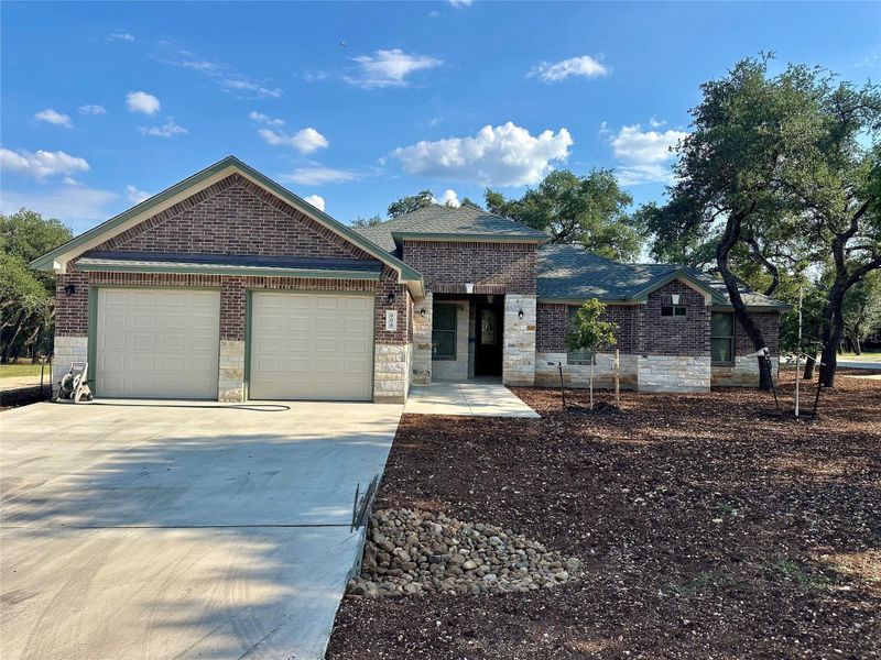Ranch-style home featuring driveway, an attached garage, brick siding, and stone siding