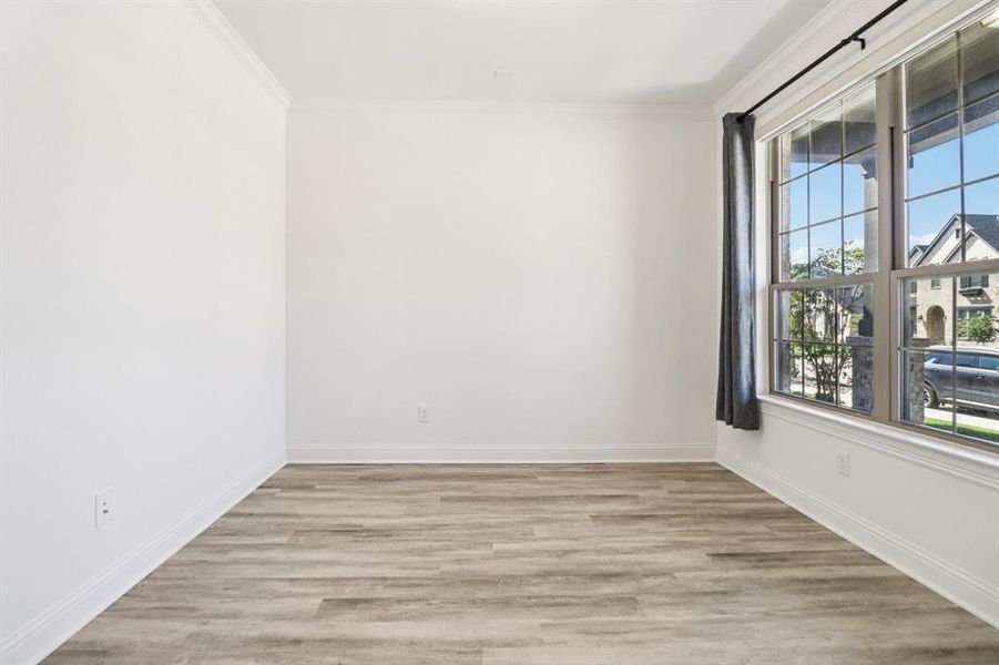 Empty room with light wood-type flooring and ornamental molding Empty room with light wood-type flooring and ornamental molding