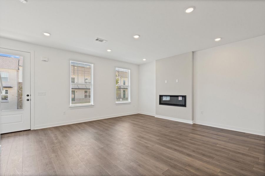 Spacious room featuring wood-finish flooring, recessed lighting, and an integrated fireplace