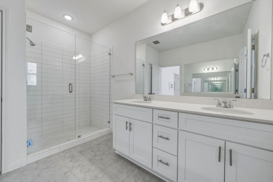 Full bath with double vanity and a shower stall