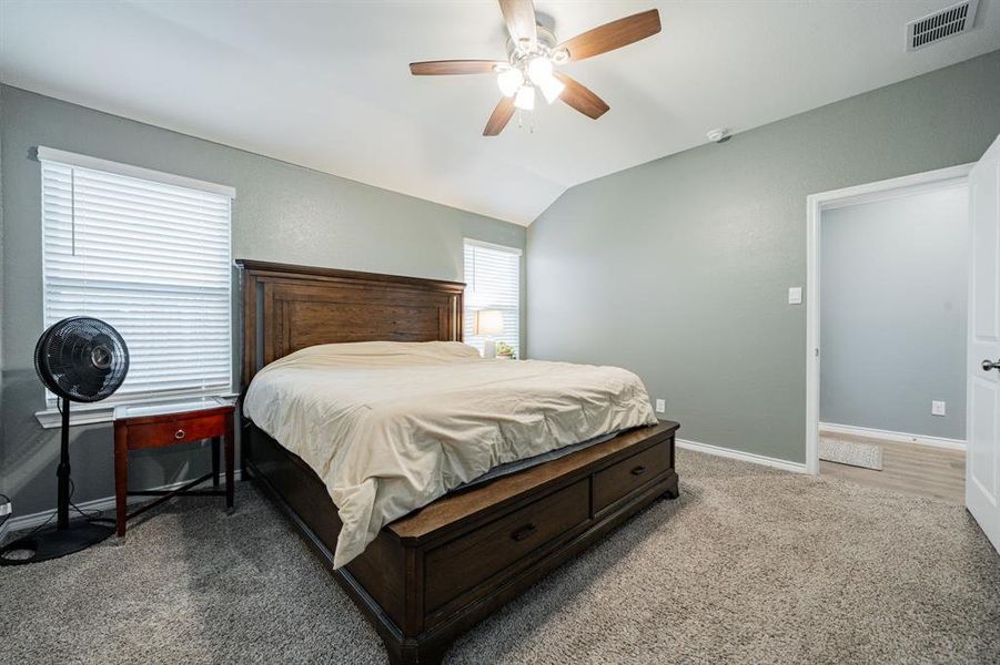Bedroom featuring light carpet, a ceiling fan, and vaulted ceiling Bedroom featuring light carpet, a ceiling fan, and vaulted ceiling