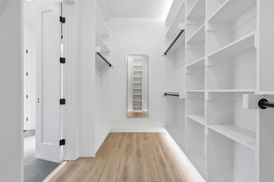 Walk in closet with light wood-style floors Walk in closet with light wood-style floors