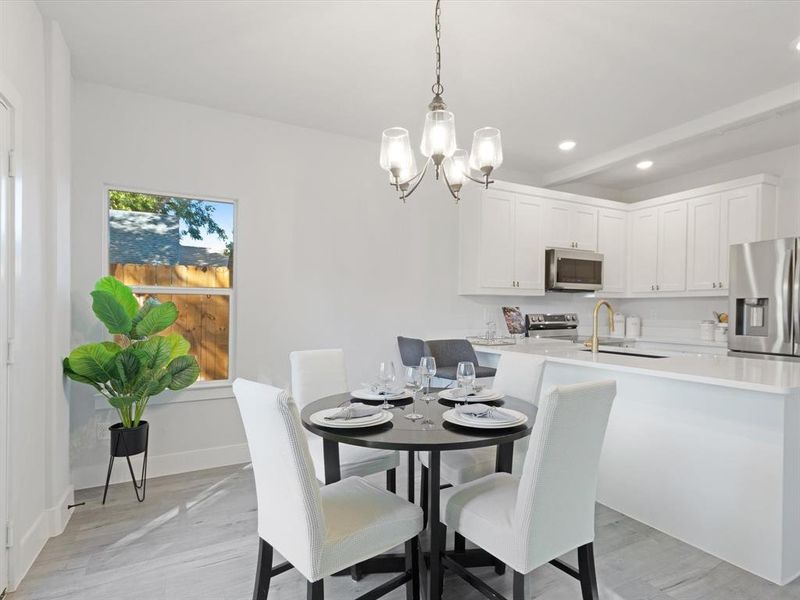 Dining area with sink, light wood-type flooring, and a notable chandelier