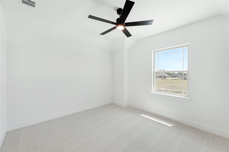 Empty bedroom with vaulted ceiling, black ceiling fan, carpet flooring, and single window with outdoor view