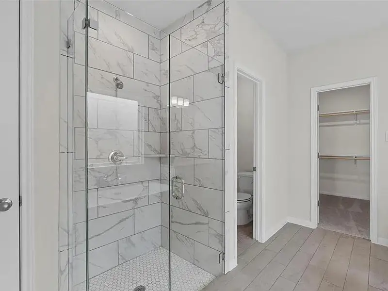A clean, modern bathroom offers a spacious walk-in shower with tile flooring.