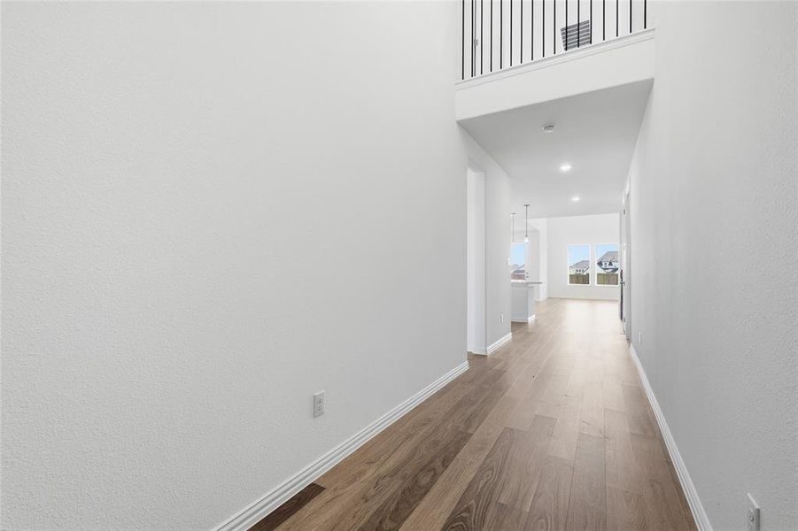 Hallway with dark wood-style floors, a high ceiling, and recessed lighting