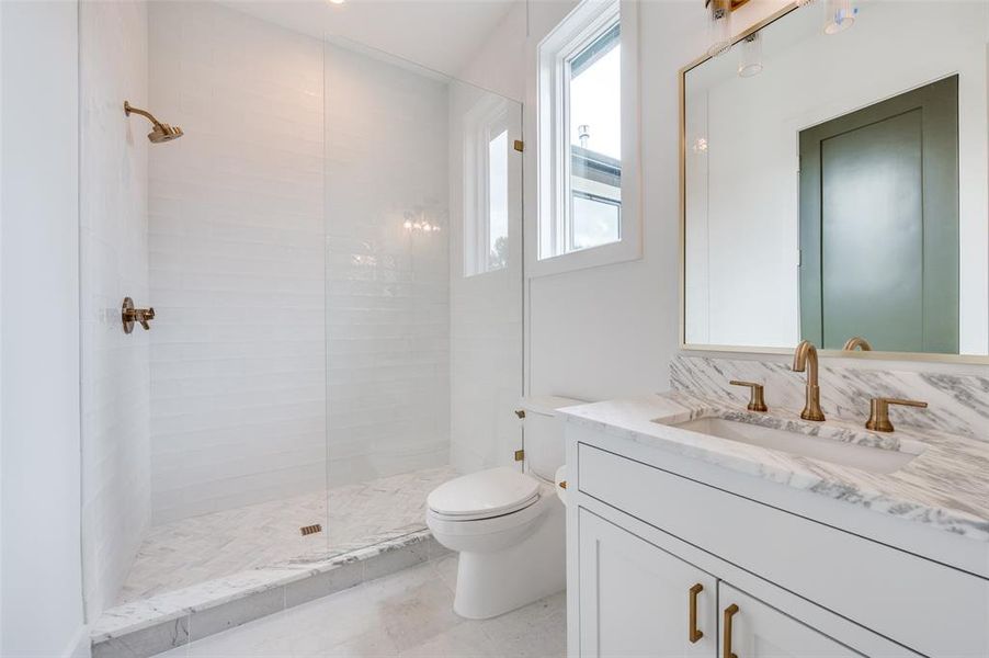 Bathroom with vanity, toilet, tile patterned floors, and a tile shower