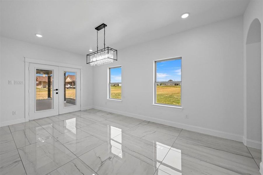 Tiled empty room featuring french doors and an inviting chandelier