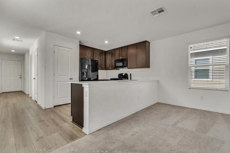 An open layout connects the kitchen to the living spaces over wood-look and carpet flooring. An open layout connects the kitchen to the living spaces over wood-look and carpet flooring.