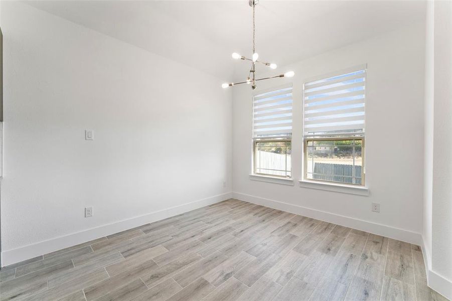 Unfurnished room with light wood-type flooring and a chandelier