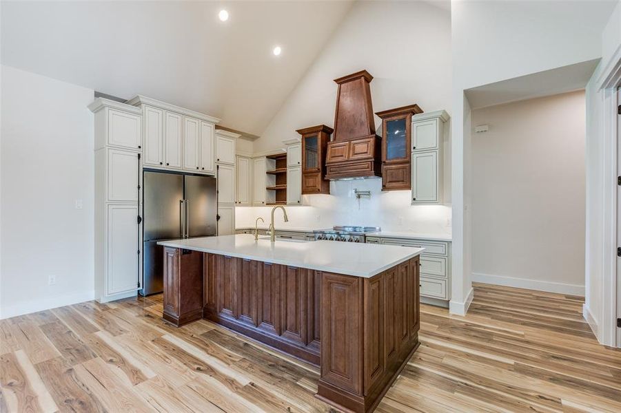 Kitchen featuring an island with sink, stove, and high vaulted ceiling