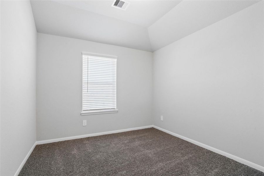 This cozy secondary bedroom offers plush soft carpeting, neutral walls ready for personalization, a sun-filled window with fitted blinds, sloped ceilings, and a spacious closet for all your storage needs.