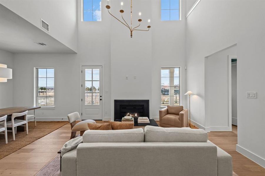 Living room featuring an inviting chandelier, light hardwood / wood-style floors, and a healthy amount of sunlight