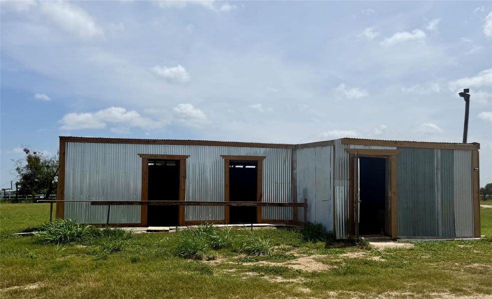 A metal-sided structure awaits its next chapter, offering versatile space on a green lot.