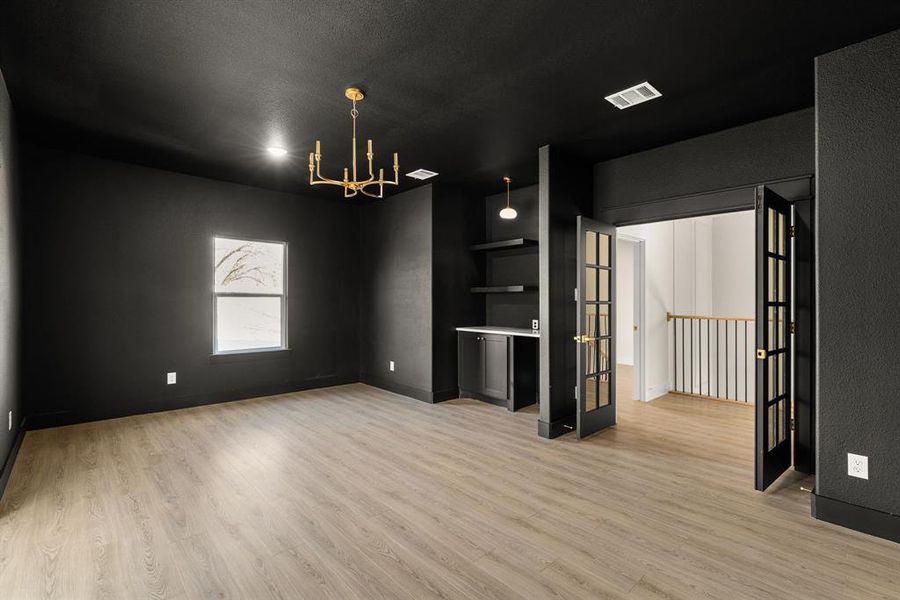 Spare room featuring light wood-type flooring, an inviting chandelier, baseboards, and visible vents