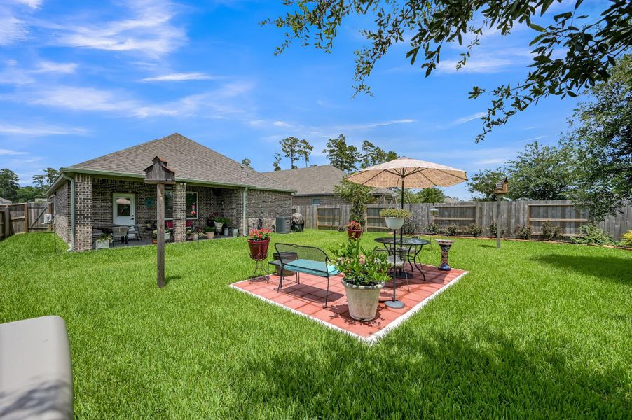 Beautifully landscaped backyard featuring an expansive lawn, custom patio seating area, mature trees, decorative garden beds, and a covered patio—creating the perfect setting for outdoor relaxation, entertaining, or enjoying peaceful evenings at home. Beautifully landscaped backyard featuring an expansive lawn, custom patio seating area, mature trees, decorative garden beds, and a covered patio—creating the perfect setting for outdoor relaxation, entertaining, or enjoying peaceful evenings at home.