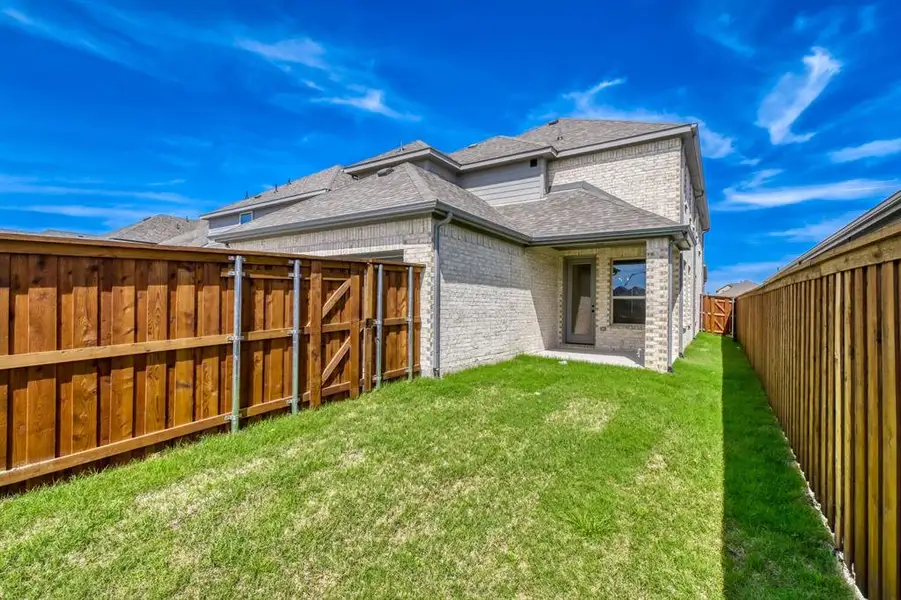 Back of property with roof with shingles, brick siding, a fenced backyard, a patio, and a gate Back of property with roof with shingles, brick siding, a fenced backyard, a patio, and a gate