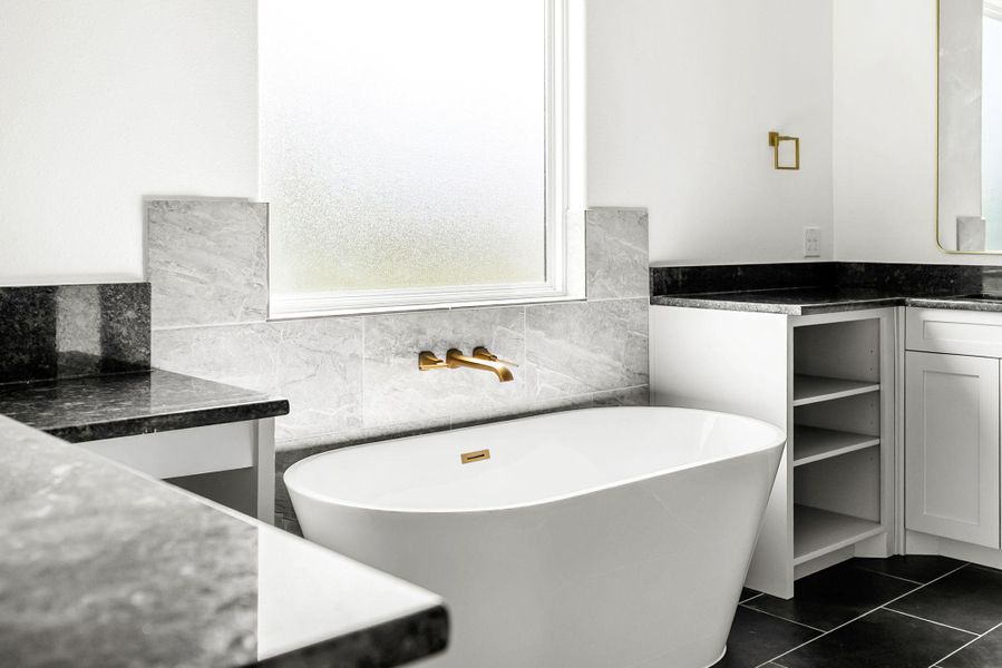 A spacious bathroom presents a clean, modern freestanding soaking tub alongside sleek vanity countertops.