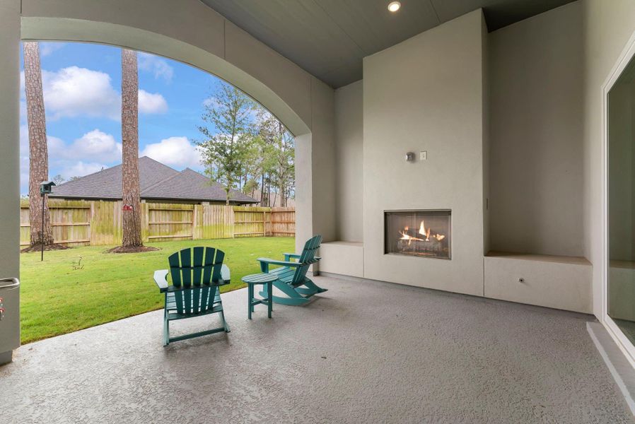 Inviting covered patio with fireplace creates a warm outdoor living space.