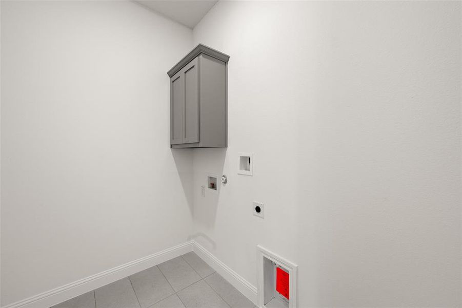Laundry room featuring hookup for an electric dryer, cabinet space, washer hookup, and light tile patterned floors Laundry room featuring hookup for an electric dryer, cabinet space, washer hookup, and light tile patterned floors