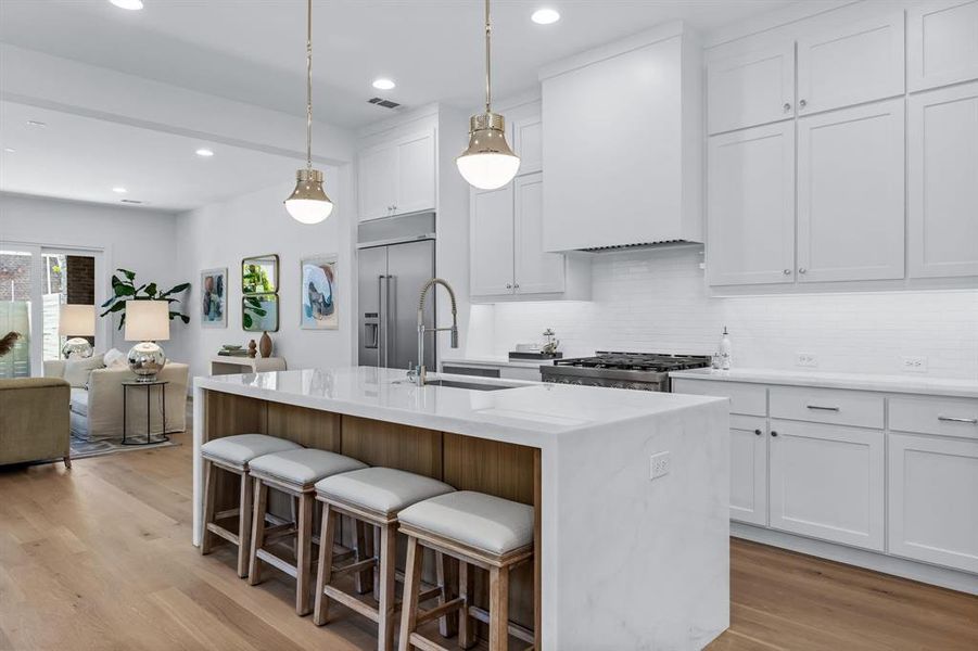 Kitchen with light hardwood / wood-style flooring, an island with sink, sink, white cabinets, and appliances with stainless steel finishes