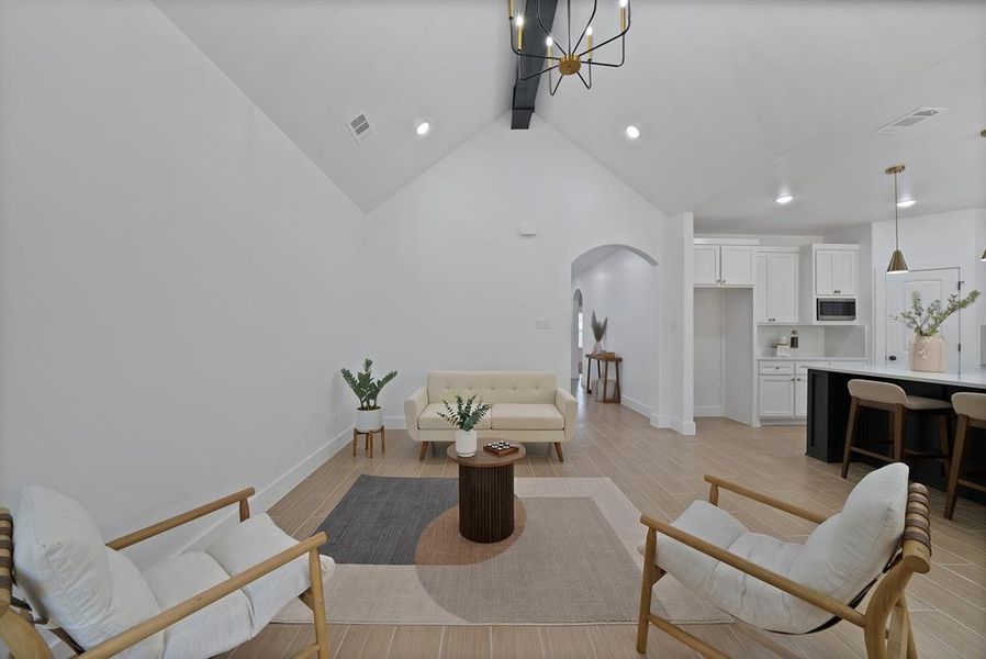Living room with beam ceiling, arched walkways, light wood-style flooring, high vaulted ceiling, and a chandelier