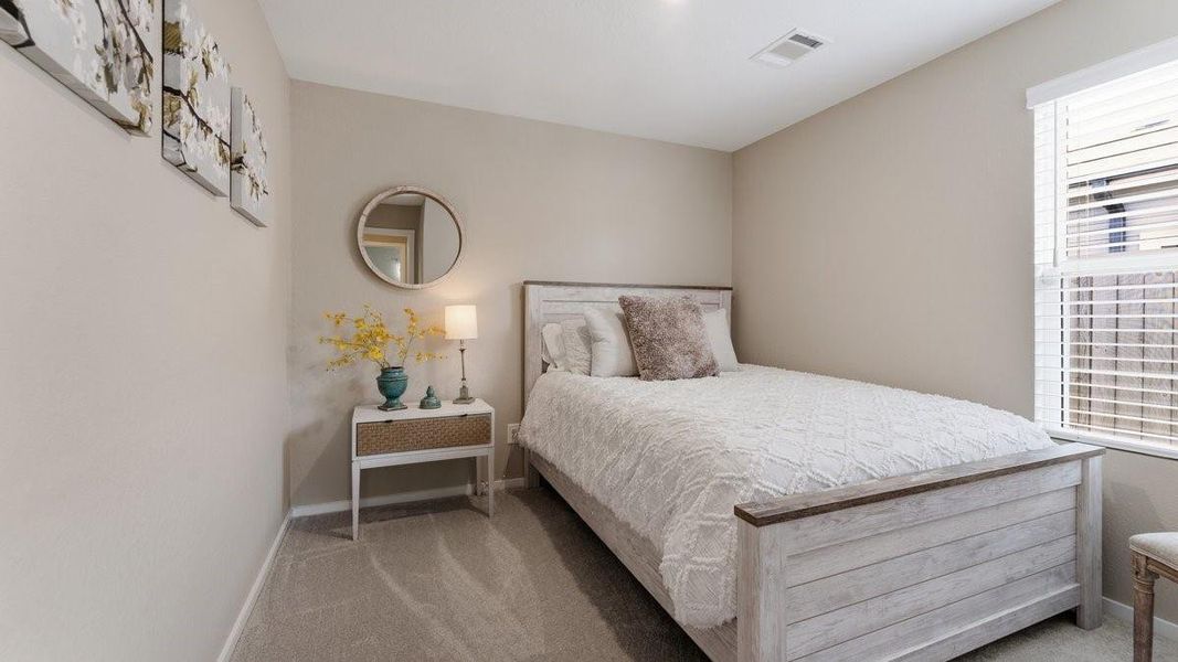 This cozy bedroom features neutral tones. A window provides natural light, enhancing the room's inviting atmosphere.