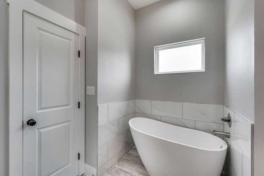 Bathroom featuring tile walls and a bath