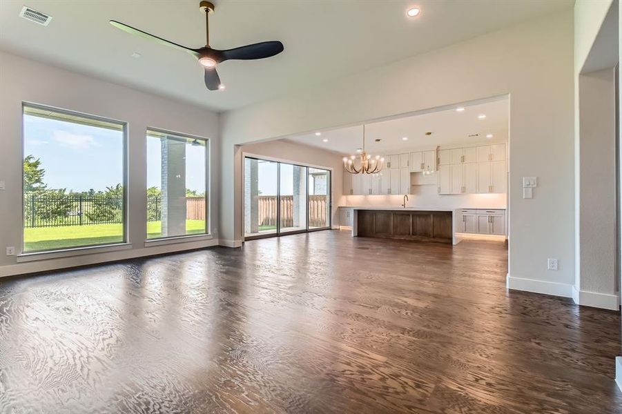 Unfurnished living room with a chandelier, recessed lighting, ceiling fan, and dark wood-type flooring Unfurnished living room with a chandelier, recessed lighting, ceiling fan, and dark wood-type flooring