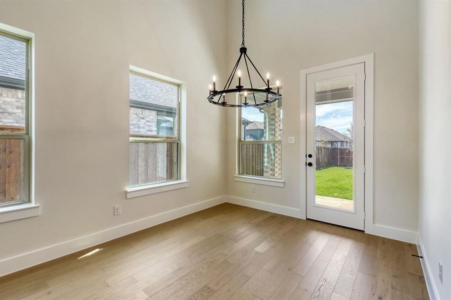 Unfurnished dining area with light wood finished floors, a chandelier, and healthy amount of natural light Unfurnished dining area with light wood finished floors, a chandelier, and healthy amount of natural light