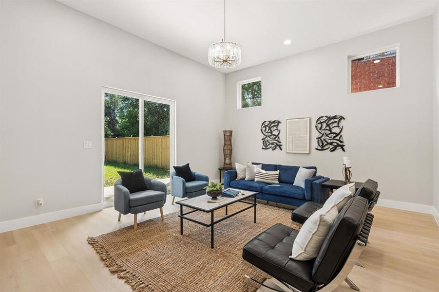 High ceilings define this living space, featuring a modern chandelier and recessed lighting High ceilings define this living space, featuring a modern chandelier and recessed lighting