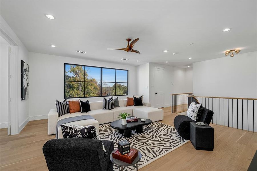 Spacious living area featuring large picture windows, wood-finish flooring, a modern ceiling fan, recessed lighting, and a contemporary metal railing