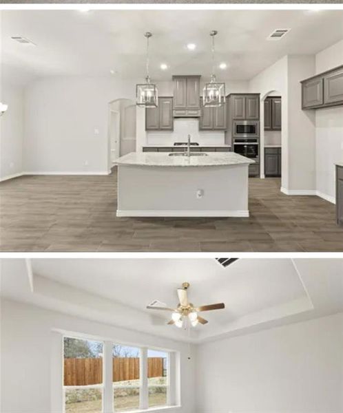 Kitchen with gray cabinets, sink, stainless steel appliances, a raised ceiling, and a center island with sink