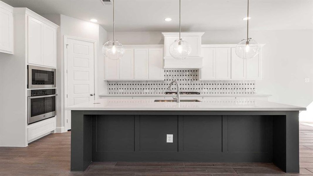 Kitchen featuring sink, stainless steel appliances, dark hardwood / wood-style flooring, and a kitchen island with sink