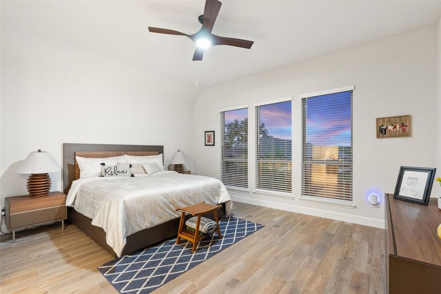 Spacious room featuring wood-finish flooring, a contemporary ceiling fan with integrated lighting, and a vaulted ceiling