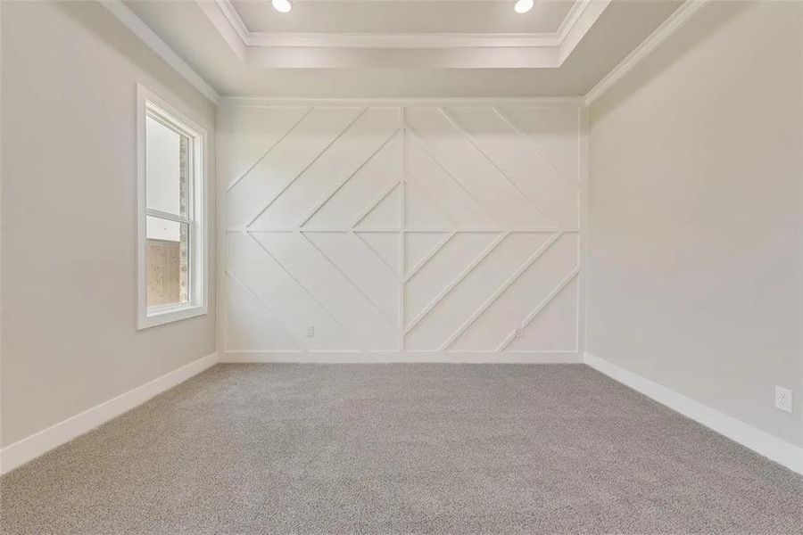 Carpeted spare room with ornamental molding and a decorative wall