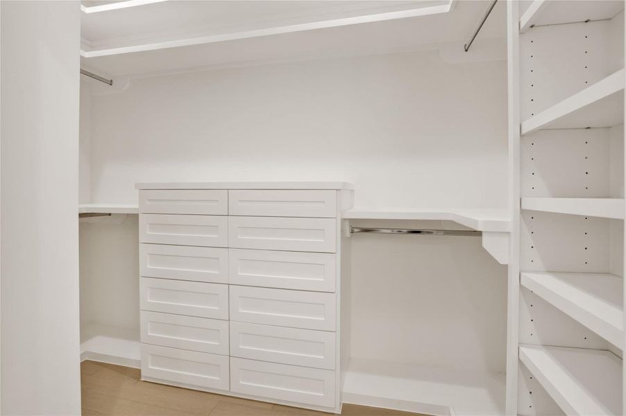 Upgraded primary closet with custom built-in drawers, shelving, and generous hanging space.