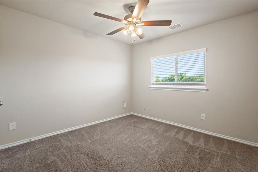Carpeted empty room featuring baseboards and ceiling fan Carpeted empty room featuring baseboards and ceiling fan