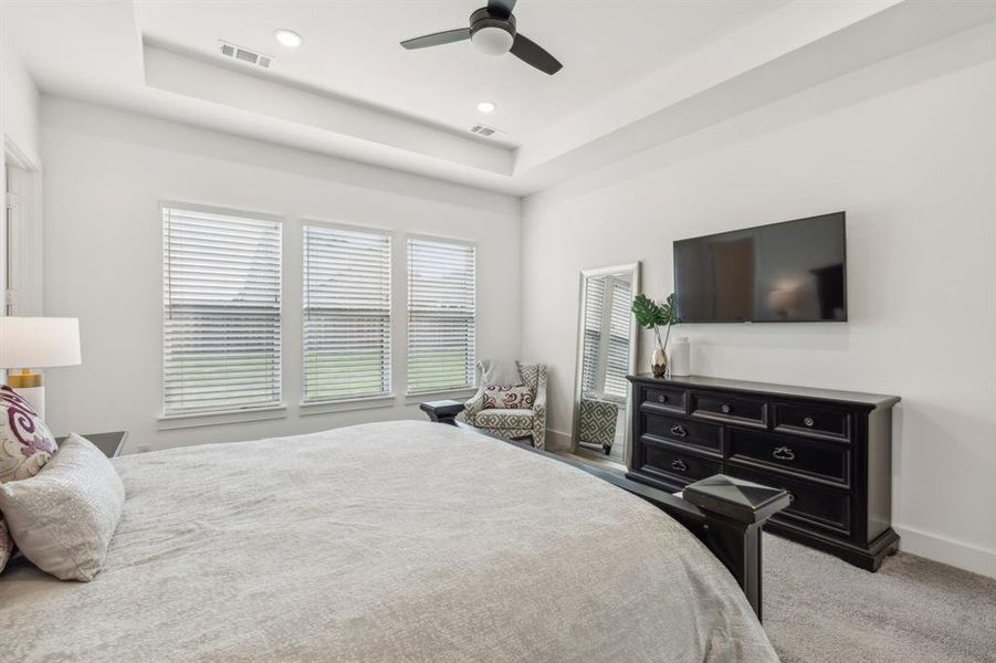 Main bedroom featuring carpet, ceiling fan, and a raised ceiling