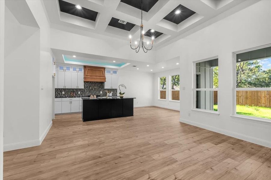 Kitchen featuring dark countertops, a chandelier, decorative backsplash, a high ceiling, and open floor plan