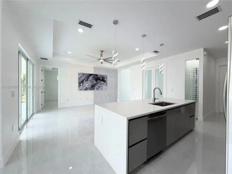 Kitchen island featuring a stone-composite countertop, undermount sink, and high-gloss cabinetry
