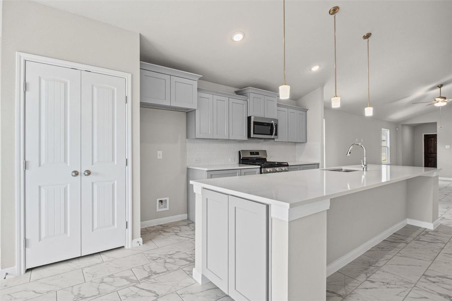 An expansive central island with stone counters anchors this modern culinary space. An expansive central island with stone counters anchors this modern culinary space.