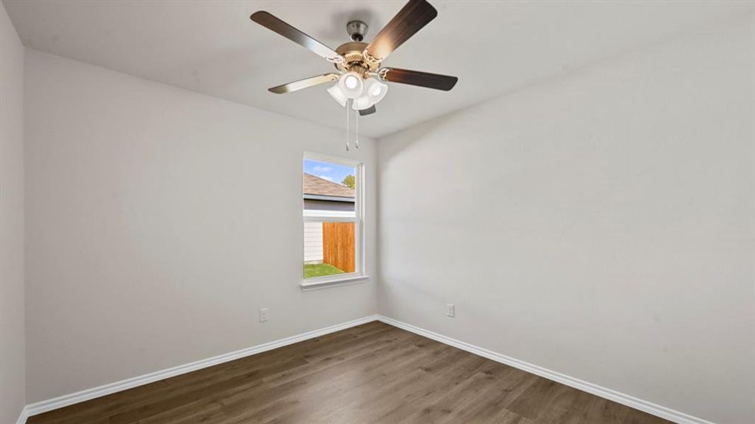 Interior room featuring wood-finish flooring, white baseboards, and light-colored walls Interior room featuring wood-finish flooring, white baseboards, and light-colored walls