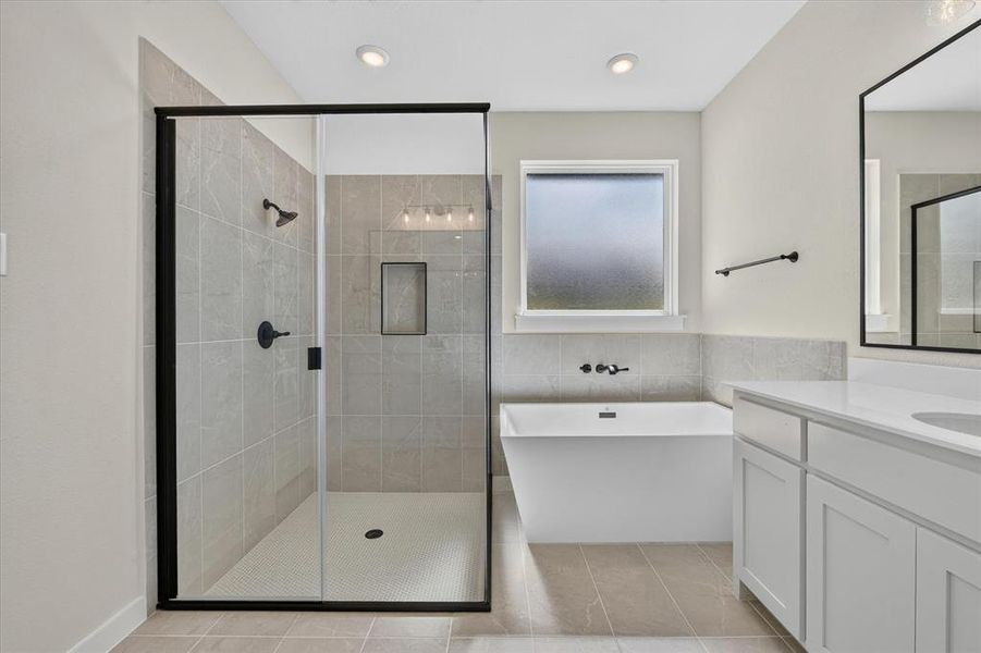 Contemporary bathroom featuring a spacious walk-in shower with black-framed glass enclosure, a freestanding soaking tub, dual vanity with white cabinetry and countertops, and modern matte black fixtures Contemporary bathroom featuring a spacious walk-in shower with black-framed glass enclosure, a freestanding soaking tub, dual vanity with white cabinetry and countertops, and modern matte black fixtures