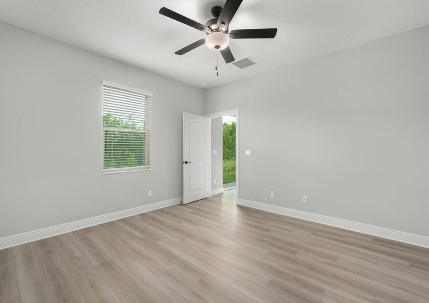 Master bedroom with a ceiling fan and window with a view of the backyard