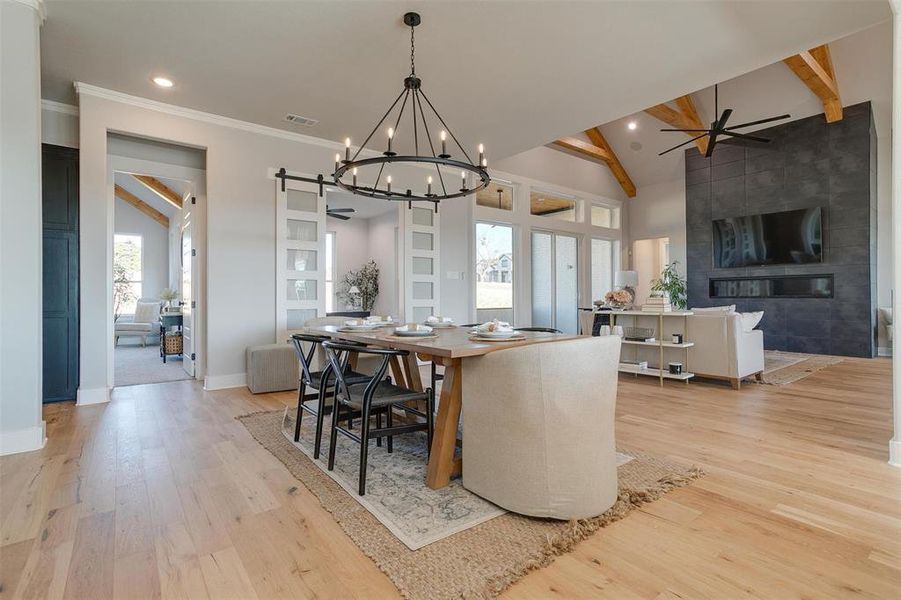 Dining area with beamed ceiling, ceiling fan with notable chandelier, light hardwood / wood-style floors, and high vaulted ceiling