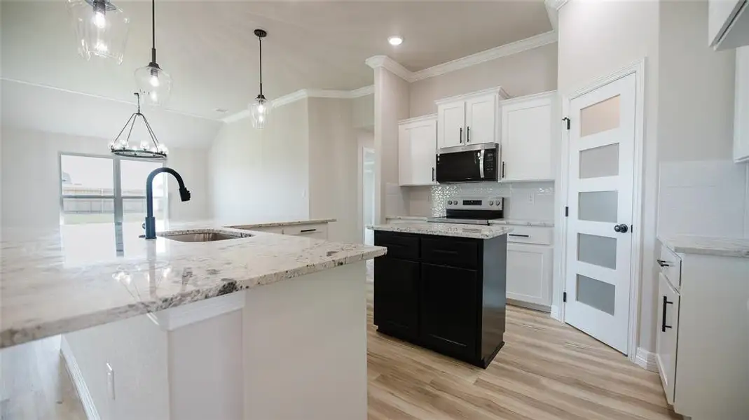 Kitchen with a kitchen island, ornamental molding, stainless steel appliances, decorative backsplash, and white cabinetry Kitchen with a kitchen island, ornamental molding, stainless steel appliances, decorative backsplash, and white cabinetry