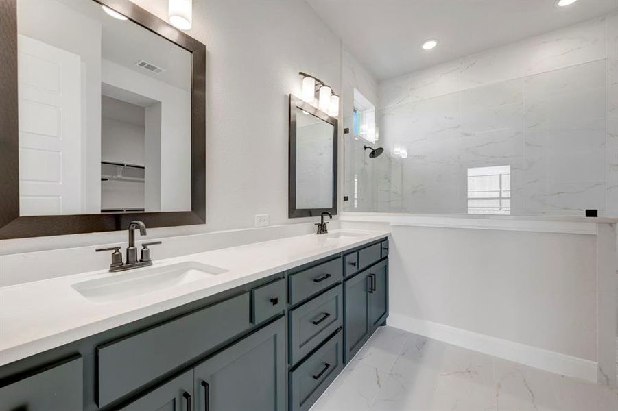 Full bath featuring double vanity, a marble finish shower, light marble finish flooring, and recessed lighting