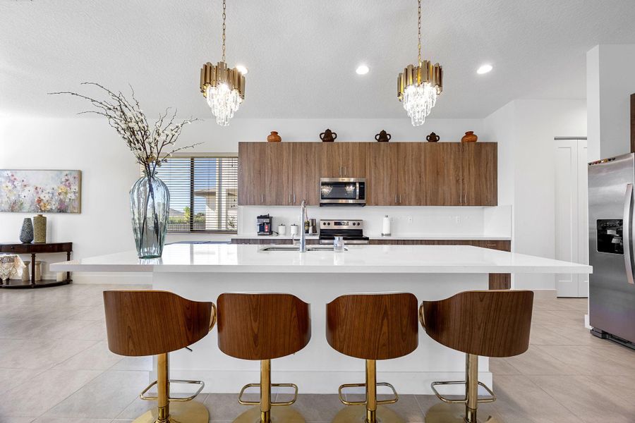 Kitchen with brown cabinetry, light tile patterned floors, modern cabinets, an island with sink, and a textured ceiling