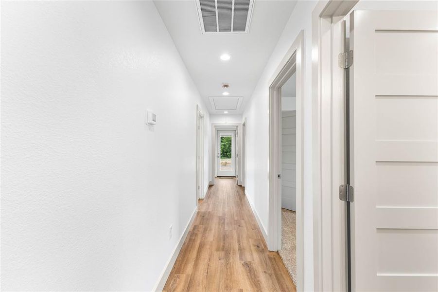 Corridor featuring light wood-type flooring, recessed lighting, baseboards, and attic access Corridor featuring light wood-type flooring, recessed lighting, baseboards, and attic access